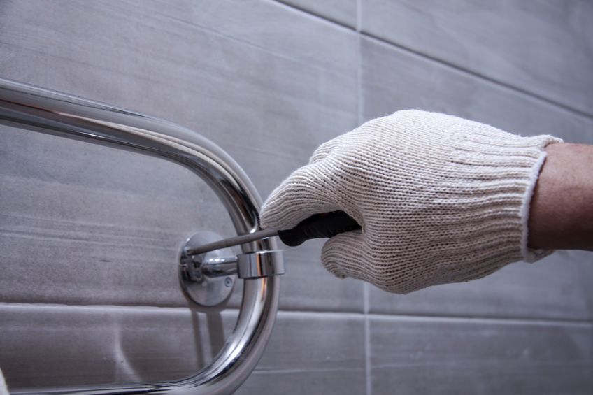 repair in the indoor bathroom. male hands of a worker in white gloves with a screwdriver